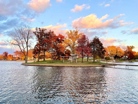 Photograph of a small island with trees in fall colors of red and yellow.