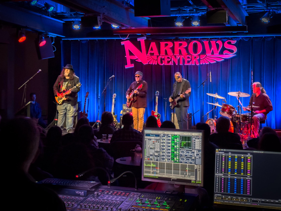 A picture of Marshall Crenshaw and his band on stage under the Narrows Center sign, with the mixing board in the foreground.
