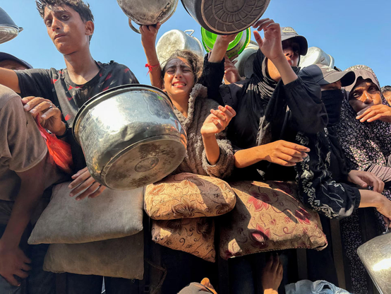 Desperate Palestinians gather to receive food from a charity kitchen.