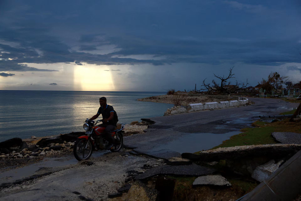A man rides a motorbike on a damaged road in the aftermath of Hurricane Melissa.