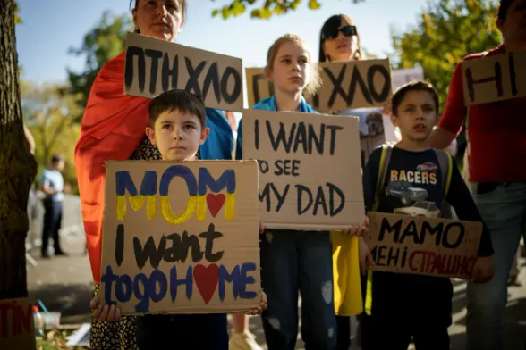 Ukrainian children hold signs reading:
I want to go home
I want to see my Dad 
Mom, I'm afraid