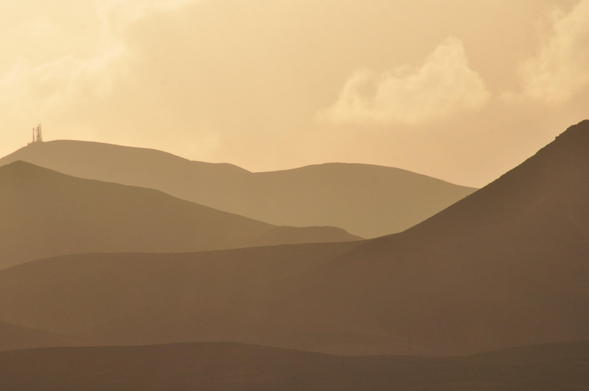 Im diffusen Licht kurz vor Sonnenaufgang modelliert der Dunst vier Kämme der "Ajaches" im Südosten von Lanzarote in monochromer Schattierung.