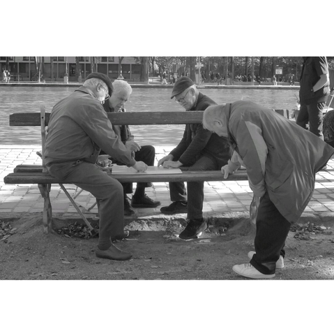 Street photography taken in Paris. Four  elderly men play dominos on a public bench near the Ourcq canal.