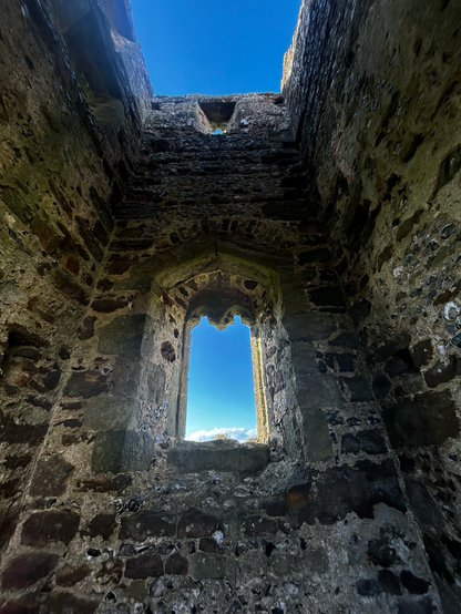 Taken from the inside of a ruined medieval church. Shows a single gothic window with no glass and a clear blue sky behind