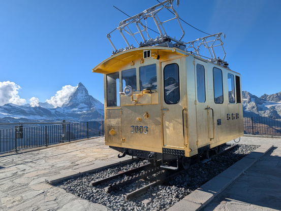 A golden railway car on Gornergrat with Matterhorn in the background 