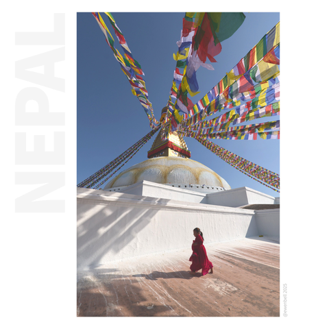 Under the prayer flags, a small child runs across the frame in contrast to the white washed walls of the stupa. 