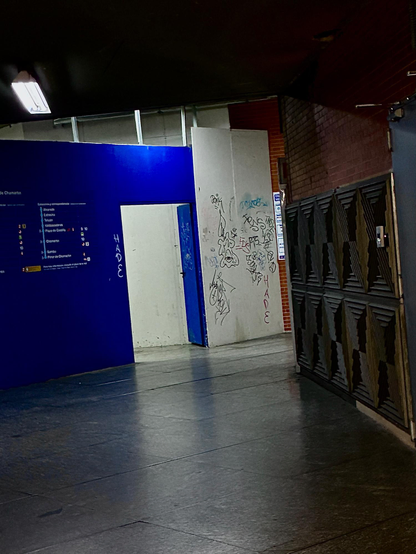 Pasillo del tren subterráneo. Paredes azules, blancas y grises. Grafitos en las blancas.