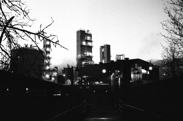 Towers with lights and an ominous glow, framed by tree branches.