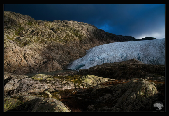 Sunlight on the rocks with a part of Folgefonna glacier. Folgefonna National Park. Norway.