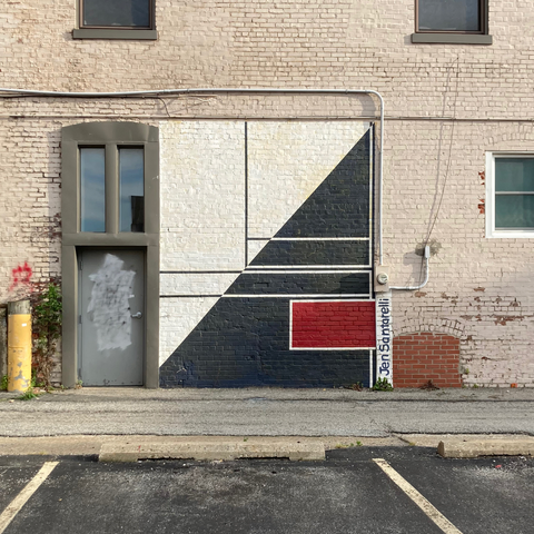 photo of abstract mural painting on a brick wall consisting of solid colors and geometric shapes