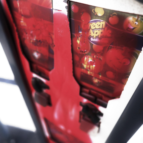 Ein Süßigkeitenautomat von schräg oben nach unten fotografiert. Er wurde allerdings mit roter Farbe verunstaltet. 