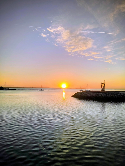 Der obere Teil des Bildes zeigt den Himmel mit einigen Wolken bei Sonnenaufgang. Der untere Teil zeigt das Meer, welches sich leicht mit Wellen kräuselt. Dazwischen die aufgehende Sonne, die sich im Meer spiegelt.
Drei Schiffe schaukeln weit entfernt im Wasser.
Links sieht man dunkles Land im Gegenlicht. Auf der rechten Seite sieht man eine Übergroße irische Harfe auf der Mole stehen.