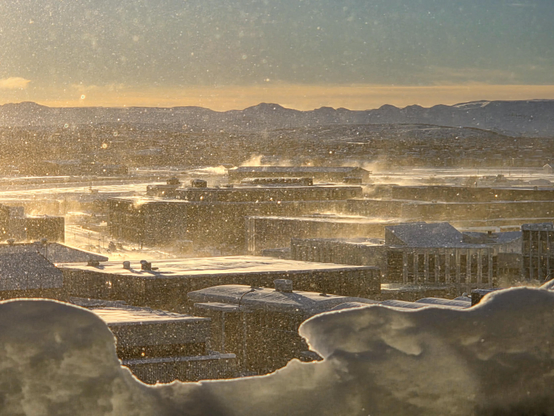 A winter scene in Reykjavík.  Snow blowing of roofs at sunrise
