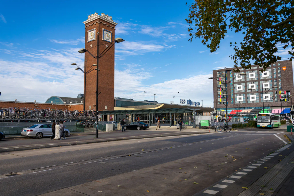 Modern-ish train station with a large brick clock tower, to the left there’s a big bike parking
