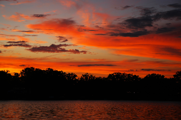 Sunset photo of a long horizontal red and orange cloud that looks a bit like the head and body of a dragon facing to the left over a lake.
