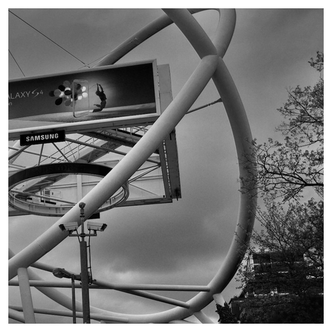 Metal framework surrounds an LED screen showing a tv advertising: A dancer is flying through a small frame balloons tied to his back.