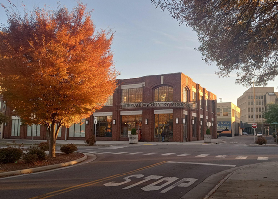 Maple with red leaves in evening light in front of brick building with large windows #autumn
