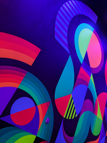 Image shows a dark wall covered with modern neon patterns lit with blacklight, at Meow Wolf Area15, Las Vegas.