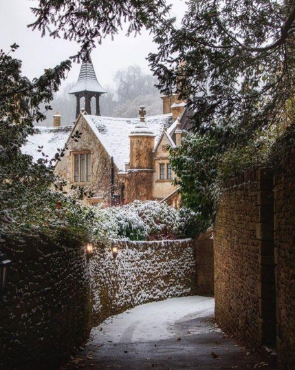 Snowed alley, frosted stone wall & roofs in an old town with a steeple.