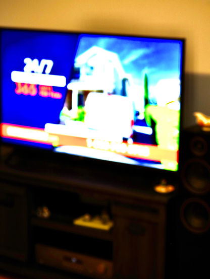 Blurry TV ON, on a stand.