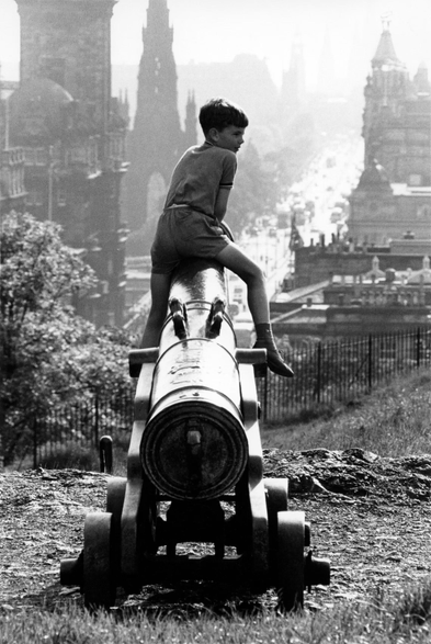 A boy sits on a cannon (?).