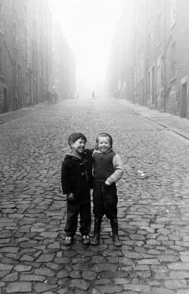 Two laughing on a misty cobbled street. B&W.
