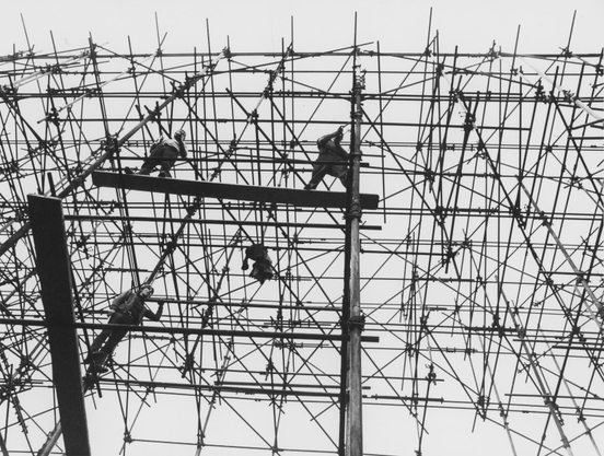Workers on a plank in a building under construction.
B&W