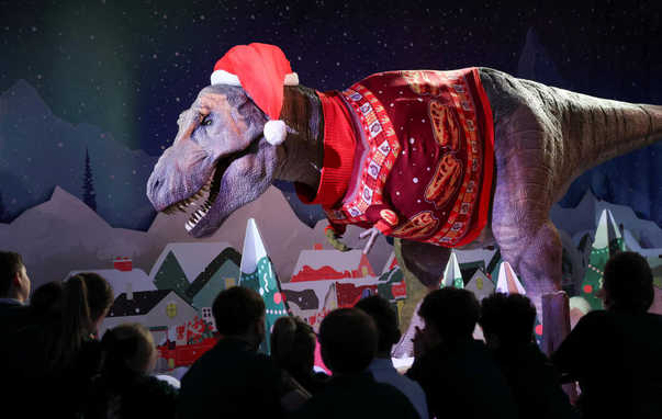 People gather around the Tyrannosaurus rex at the Natural History Museum, part of the museum’s festive Christmas display.