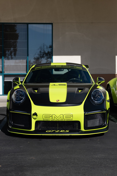 A bright highlighter green coupe. A carbon hood and black decals cut down the bright colors on its front.