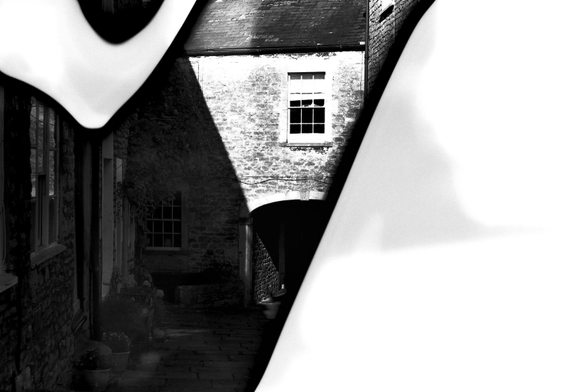 An old cobbled courtyard with stone buldings circa 1820s on either side.  At the end of the courtyard, the path passes through an archway. The scene is shot in bright sunlight with a the difference between light and shade is quite harsh.  The right third of the image is white due to development failures as is an area of the top left hand corner which is a kind of a lossenge shape area. They sort of mar the image and yet add an extra quaility to it.  