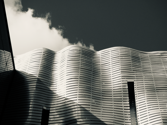 A detail of the curvy metal facade of the Old Brewery in Poznań against cloudy skies
