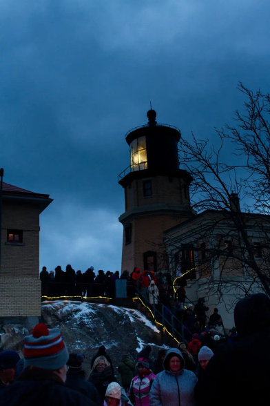 Split rock lighthouse lit up, with a crowd of people