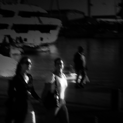 Lesbians stroll along the harbor holding hands.
Blurry photo black and white
