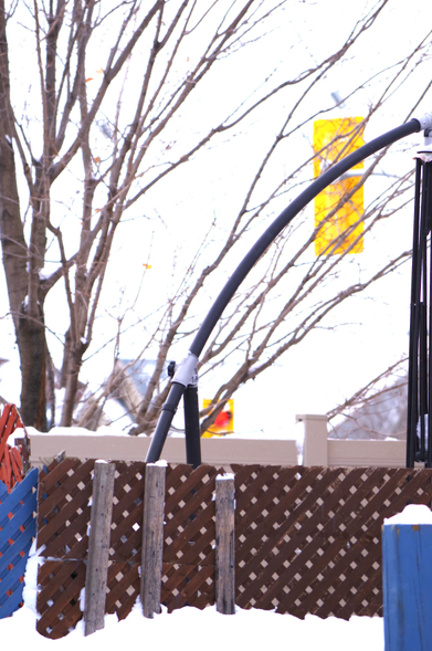 Some sparse autumn colours on trees and bushes on streets near fences and traffic lights after a snowfall.