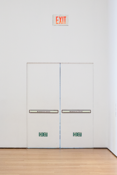 Two wide, white exit doors on a similarly stark white wall with the high contrast EXIT sign above it. 
