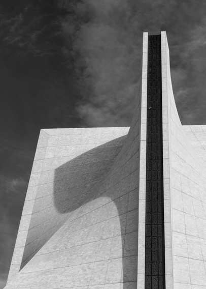 A black and white photo of the roof of St Mary's cathedral in San Francisco, with the late afternoon sun casting a long and curved shadow across the unusual roof.