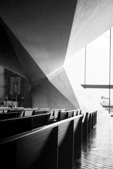 A black and white photo of rows of pews in St Mary's cathedral in San Francisco, with one of the interior columns in the background.