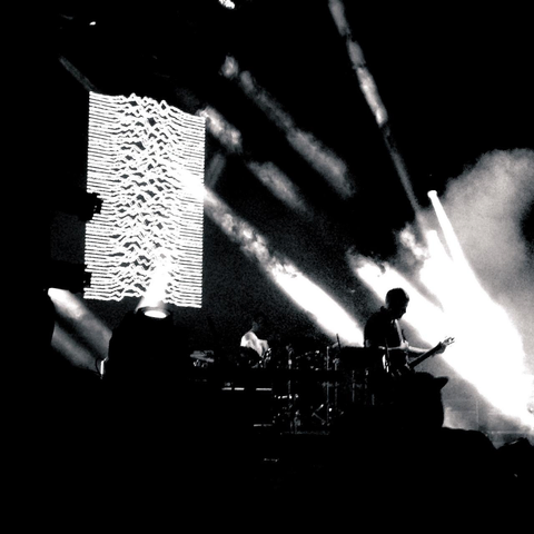 Silhouette of a guitarist against a light projection of wavy lines