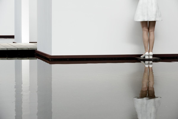 legs of a statue in a museum, reflected in water
