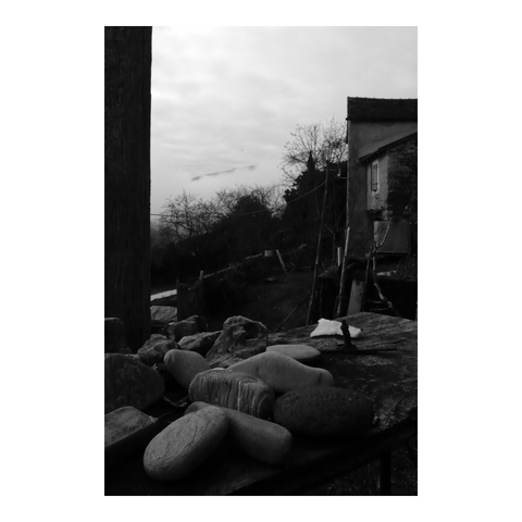 A collection of pebbles placed on a board on the railing of a balcony overlooking the valley. (Version françæ) Collection de galets posæ sur æn planche posæ sur læ rambarde d’æn balcon avec vue sur læ vallée.