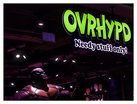 En liggande bild på en neonskylt vid ett skyltfönster. Texten är ”OVRHYPD Needy stuff only!” i grönt och svart. Nere till vänster ses en docka av en man, i övrigt är det ganska mörkt.