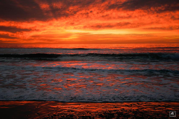 Color photo of a scene from a beach during a very colorful sunset. 