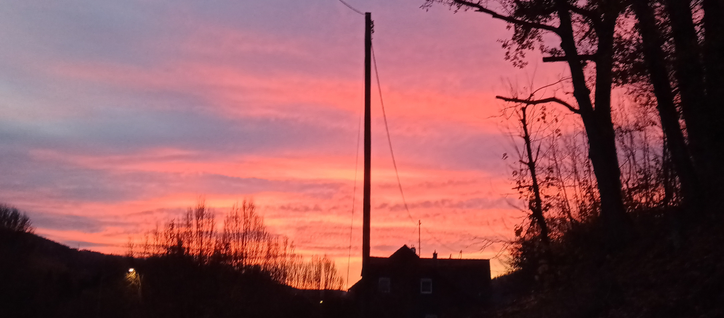 Dunkle Haus/Baum Silhouette und darüber ein rot blauer Abendhimmel 