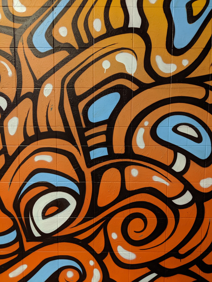 English: Image displays a graffiti mural on a wall outside a rail station in Sydney. The image has orange swirls outlined with black, and a few baby blue highlights. 

Deutsch: Das Bild zeigt ein Graffiti-Wandbild an einer Außenwand eines Bahnhofs in Sydney. Es besteht aus orangefarbenen, schwarz umrandeten Wirbeln und einigen hellblauen Akzenten.

Español: La imagen muestra un mural de grafiti en una pared exterior de una estación de tren en Sídney. La imagen tiene espirales naranjas delineadas en negro y algunos detalles en azul celeste.

Français : L’image montre une fresque de graffiti sur un mur extérieur d’une gare de Sydney. L’image présente des volutes orange cernées de noir et quelques touches de bleu clair.

Türkçe: Görselde, Sidney'deki bir tren istasyonunun dışındaki bir duvarda bulunan bir grafiti resmi yer alıyor. Görselde, siyahla çevrelenmiş turuncu girdaplar ve birkaç bebek mavisi vurgu bulunuyor.

تُظهر الصورة جدارية جرافيتي على جدار خارج محطة قطار في سيدني. تتخلل الصورة دوامات برتقالية محاطة بالأسود، وبعض اللمسات الزرقاء الفاتحة.