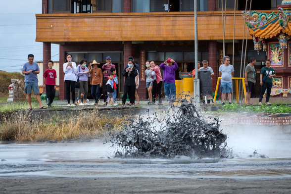 Crowds gather to watch the eruption of a mud volcano.