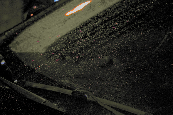 Windshield and wipers idle in a black rain at night.