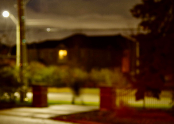 A blurry person walking near a blurry residential street.