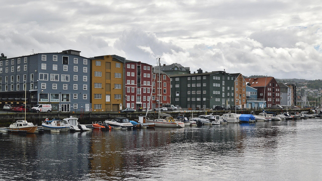 A photo of colorful buildings along a canal. The sky is filled with clouds.