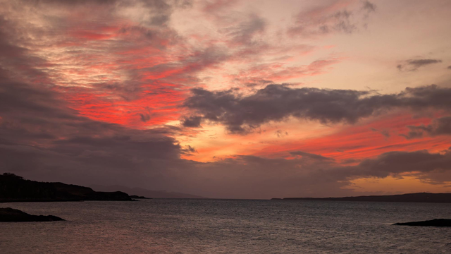 Pretty sunset colours over a sea loch as the sun goes down in thinly clouded skies, reds, peaches and warm greys for colour. 