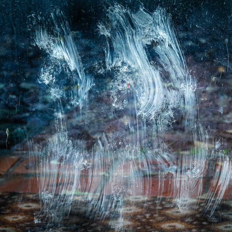 Mostly abstract photograph of smeared dirt on a window caused by a cat's paws. 